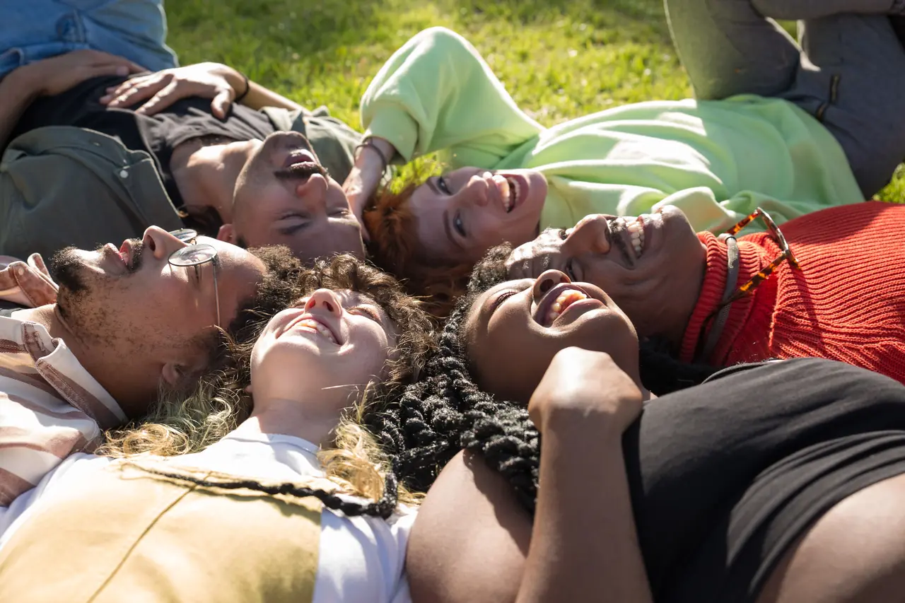 Friends lying in a circle on the grass, laughing together